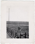 A young girl poses in front of a small fenced in garden, provided by the relief workers at Rivesaltes.