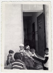 A group of Jewish children stand outside of a building in Rivesaltes; two are carrying a bench.
