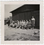 Survivors of the Buchenwald concentration camp, many with crutches, sit outside a barrack following liberation.