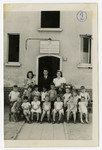 The founder and principal of the Henrietta Szold Hebrew School, Solomon Manischewitz, and two teachers stand behind the first grade students at the enrance of the school at the Zeilsheim DP center.