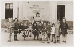 Jewish DP children at the Cremona displaced persons camp pose outside the Chaim Nachman Bialik school holding rakes and hoes.