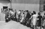 Jewish DPs carrying lunch pails wait in line outside a food distribution center in an unidentified displaced persons camp.