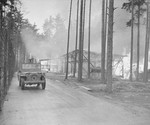 An American soldier drives past buildings set afire by survivors after the SS evacuated the Ohrdruf concentration camp.