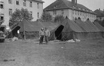 American medical personnel stand in front of two tents set up outside a school which has been converted into a hospital for concentration camp survivors from Langenstein-Zwieberge.