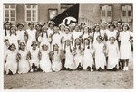 Group portrait of German girls posing outside their school in front of a Nazi flag.