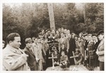 A large group of Jewish displaced persons poses next to two graves marked with wooden crosses in Lueneburg.