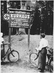 Berta Spiro and Hans Israel examine a Nazi sign declaring that Israeldorf is six kilometers away while on a bicycle trip through Germany.