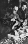 Two men fashion wooden clogs in the shoemaking workshop in the Kovno ghetto.