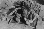 The charred corpses of Rabbi Shmukliarski, his wife and son on a makeshift stretcher after the razing of the Kovno ghetto.