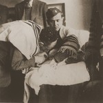 Chaplain Mayer Abramowitz holds a newborn during a circumcision ceremony at the Schlachtensee displaced persons camp.
