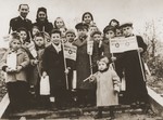 Group portrait of children holding toy flags for Simchat Torah at the Schlachtensee displaced persons camp.