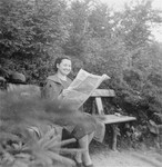 Portrait of the donor, Magda Herzog Muller, reading a newspaper on a park bench in the Czech resort of Trencianske-Teplice.