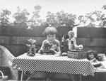 A young Jewish child sits at a table full of toys on the terrace of her home in Leipzig.