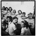 A group of children sits around a table in the Ferramonti internment camp.