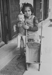 A young Jewish DP girl poses with a doll and toy stroller in the Feldafing displaced persons camp.