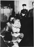 An unidentified man signs a document at the Sachsenhausen concentration camp war crimes trial in Berlin.