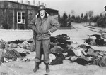 An American soldier stands in front of a large number of corpses that are strewn along the road in the newly liberated Ohrdruf concentration camp.