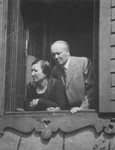 Dr. Adolf and Paula Huber look out the window of their home.