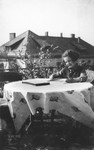 A young Jewish girl sits at a table on the porch of her home.