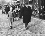 A Jewish father and son walk along a commercial street in Prague.