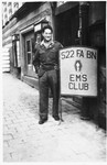 Clarence Matsumura, a Japanese-American soldier in the 522nd Field Artillery Battalion in Germany, poses next to a 522 EMS club sign.