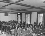 Spectators await the return of the judges for sentencing during the trial of 74 SS men charged with perpetrating the Malmedy atrocity.