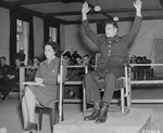 Former U.S. Army sergeant Kenneth Ahrens demonstrates how he surrendered to SS soldiers, during his testimony at the trial of 74 SS men charged with perpetrating the Malmedy atrocity.