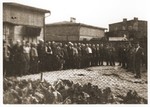 Ghetto police guard a group of Jewish men who have been lined up in the yard of the central prison of the Lodz ghetto.