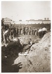 American soldiers look on as Austrian civilians lay the bodies of former inmates in a mass grave in the Mauthausen concentration camp.
