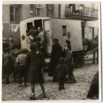 A young child is carried into a horse-drawn ambulance while other children gather around to watch.