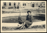 Close-up portrait of a young female censor for the American army sitting on the edge of a fountain in the Deggendorf displaced person.