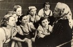 Stella Rein, the headmaster of the Lodz ghetto's high-school, talks to a group of young girls wearing similar blouses.