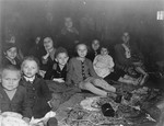 Women and children survivors sit on the floor of a barracks in the newly liberated Gunskirchen concentration camp.