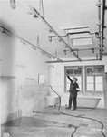 A member of the French resistance points to pipes in the shower room of Natzweiler-Struthof from which prisoners were hung and beaten by SS guards.