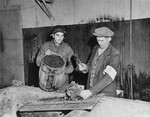 A member of the French resistance demonstrates for an American soldier the method of preparing chopped potatoes, the staple of the inmates' diet.