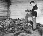 A young member of the French resistance examines boots, shoes, and wooden clogs piled near a furnace in the crematorium of the Natzweiler-Struthof concentration camp.