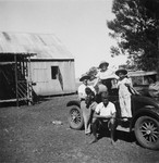 Members of a Jewish refugee family pose with an African assistant in front of their car on their farm in Kenya.
