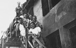 Members of Kibbutz Maestro pose by the railing of the outside steps to a building.
