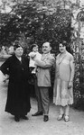Three generations of a Jewish Slovak family pose for a portrait in a park.