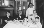 A Jewish family poses with their hired help at the dinner table in their home in Harbin, China.