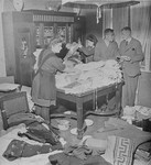 Ilse Kohra(L), the daughter of the Burgermeister of the German town of Belsen, along with Herr Pfeifer(R) and his daughter Anna, sorting clothing for Bergen-Belsen survivors in the Burgermeister's house.