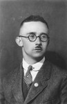 Studio portrait of Heinrich Himmler wearing a Nazi party pin on his lapel.