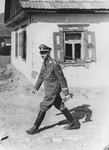 Reichsfuehrer-SS Heinrich Himmler walks past a cottage [probably during a visit to the Waffen-SS Armored Division Wiking].