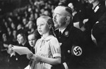Reichsfuehrer-SS Heinrich Himmler holding his daughter Gudrun while seated in an audience.