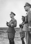 Reichsfuehrer-SS Heinrich Himmler stands outside in a field holding a pair of binoculars in the company of Paul Hausser (second from the right) and Ludolf-Hermann 
von Alvensleben, Himmler's adjutant at the time.
