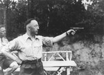 Heinrich Himmler shoots a pistol while Kiermaier watches in the background.