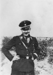 Reichsfuehrer-SS Heinrich Himmler poses outside in uniform with his hands on his hips.