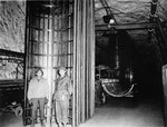Two American soldiers stand next to a completed half-section of a V-2 fuselage in the underground rocket factory at Dora-Mittelbau.