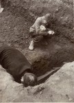 A Polish boy, Michael Kallaur, weeps while helping his father bury the body of his grandmother, Elizabeth Kallaur, who died in the Nordhausen concentration camp.