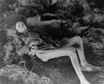 An emaciated survivor lies inside a barrack on a pile of straw in the newly liberated Nordhausen concentration camp.